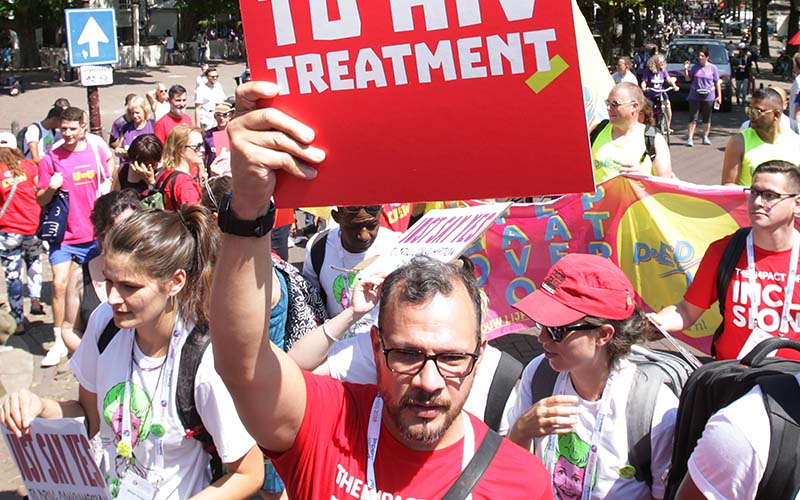 A man with a sign that says "Treatment" at a protest.